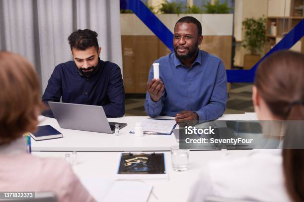 Young Africanamerican Pharmacologist Presenting New Medicament Stock Photo - Download Image Now