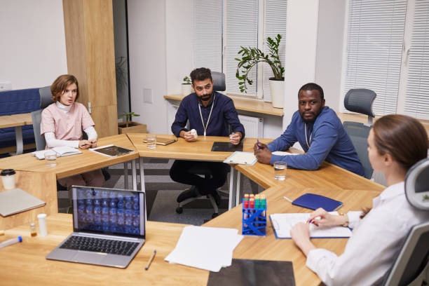 cuatro jóvenes expertos contemporáneos discuten los resultados de la investigación clínica - exam business caucasian board room fotografías e imágenes de stock