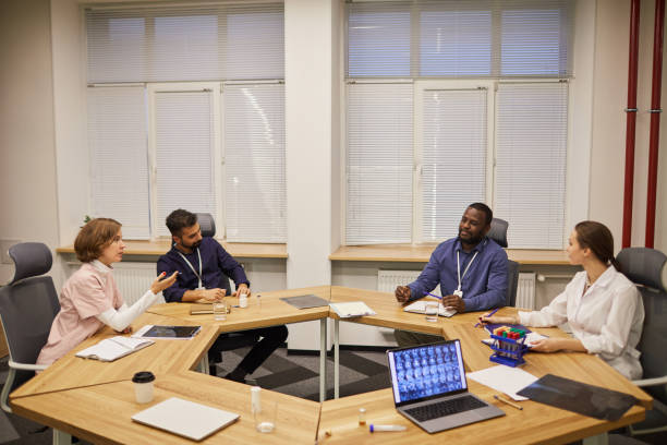 istock Four young contemporary experts sitting by round table during discussion 1371822393