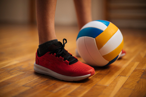 Close-up shot of sneakers, a young man's legs and a ball