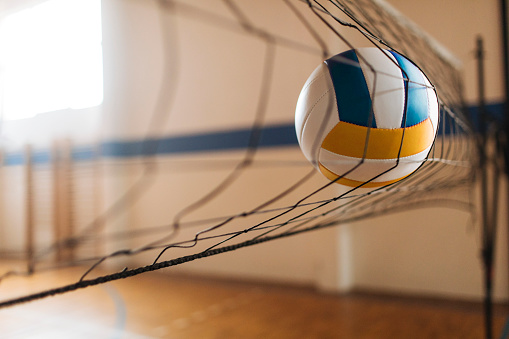 Female volleyball player spiking the ball during game at sports court