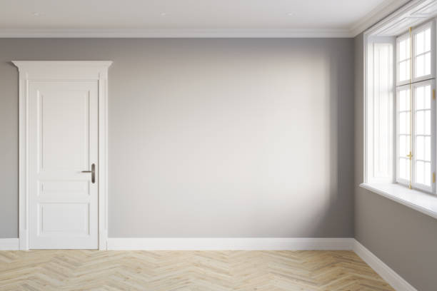 istock Modern-classic empty room without furniture with a blank gray wall between white classical door and window without curtains, light parquet floor. Front view. 1371824856