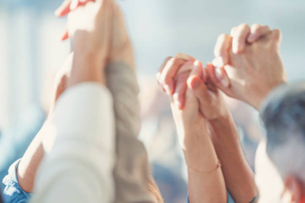 istock Group of workers holding hands in celebration. 1371824950