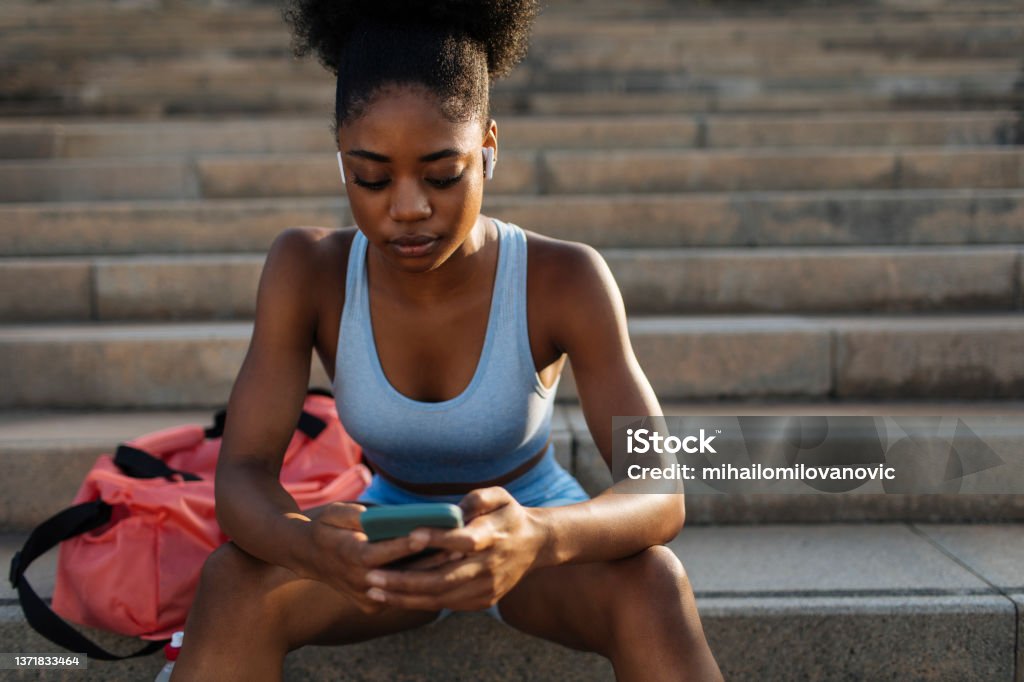 Waiting for you at the field Young athletic woman using her cellphone before working out Healthy Lifestyle Stock Photo