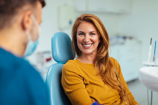 Smiling red haired woman listening to her dentist while sitting in his office