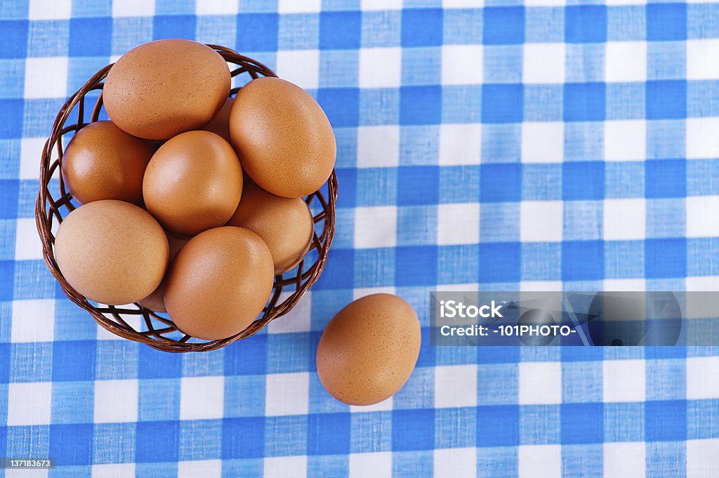 brown eggs against the background of the table with checkered tablecloth, brown eggs in wicker basket Animal Egg Stock Photo