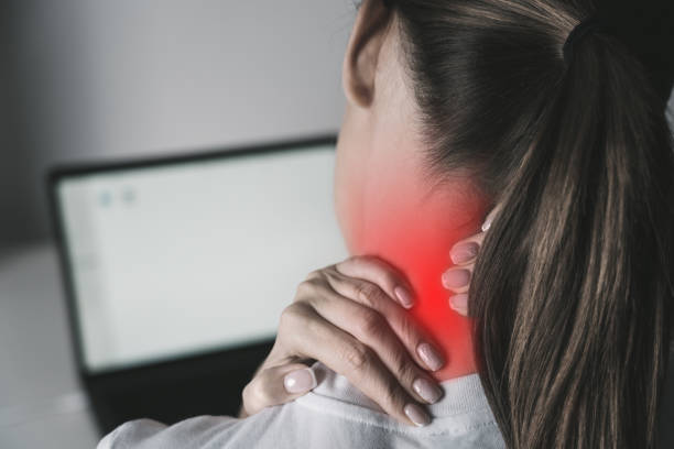 mujer que sufre de dolor de cuello después de trabajar en una computadora portátil - clostridium fotografías e imágenes de stock