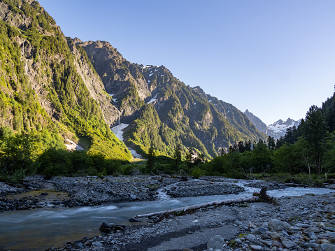 A view of the Quinault river flowing through Enchanted Valley in Olympic National Park, braided riverbank and towering cliffs.
