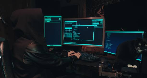 istock Hacker in a hood sits in front of computer screens and hacks databases 1371841929
