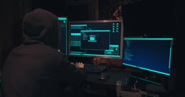 istock Hacker in a hood sits in front of computer screens and hacks databases 1371841941