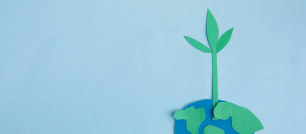 Cute children's paper applique -a model of the Earth and a young sprout on a blue background. Creative concept Earth Day, Earth Hour, copy space for text stock photo