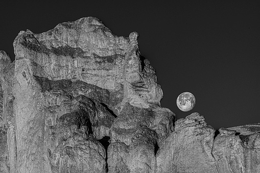 Full Moon at early morning above dramatic cliffs of Smith Rock