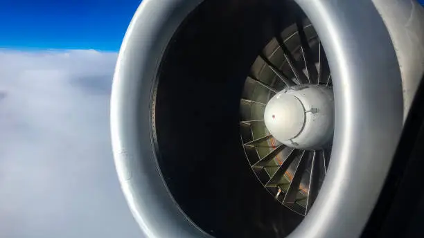 Photo of Close-up of Jet Engine Flying Over Clouds with Blue Sky