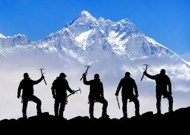 View of mount Lhotse and silhouette of group of five climbers with ice axe in hand, Everest area Khumbu valley, Sagarmatha national park, Nepal