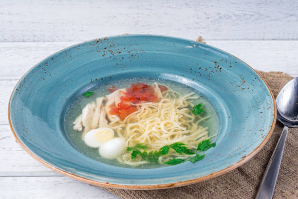 istock Chicken soup bouillon in a plate on white wooden table 1371854994