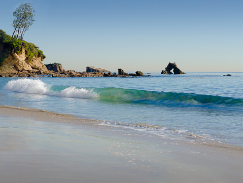 Offshore rock formations and waves breaking onto the shore give character to a popular beach in Corona del Mar, California.