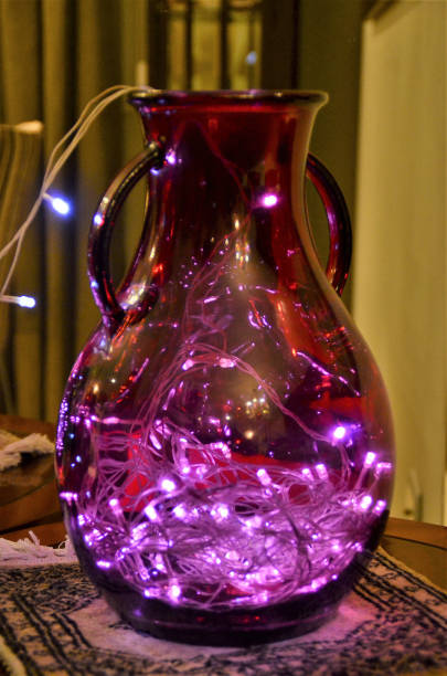 A Christmas decoration with a red glass jug with LED light inside