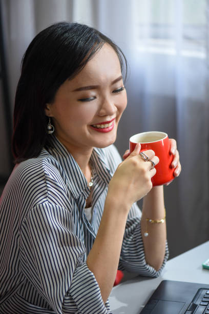 Beautiful Asian business woman take a break while working at office Fashionable business woman with luxury accessories such as diamond ring and silver bracelet while holding a cup of coffee at office diamond earring stock pictures, royalty-free photos & images