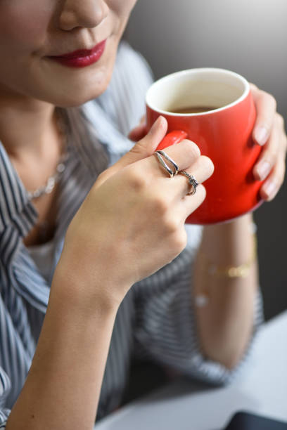 Fashionable business woman with luxury accessories such as diamond ring and silver bracelet while holding a cup of coffee at office