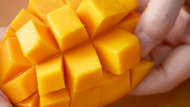 Cutting fresh mango fruit and showing the juicy diced pulp.