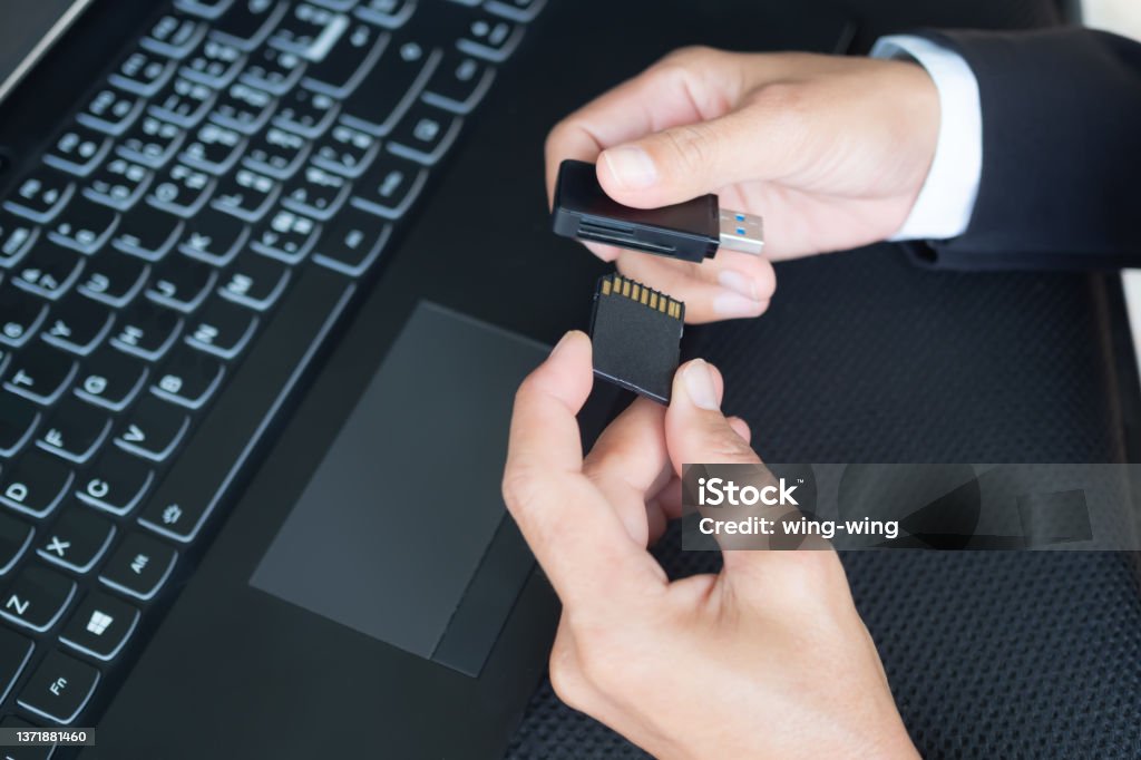 Hand with black suit holding memory sd card and card reader for copy data from camery to laptop computer Hand with black suit holding memory sd card and card reader for copy data from camery to laptop computer. staff woman working document in office. techonlogy for business concept. Memory Card Stock Photo