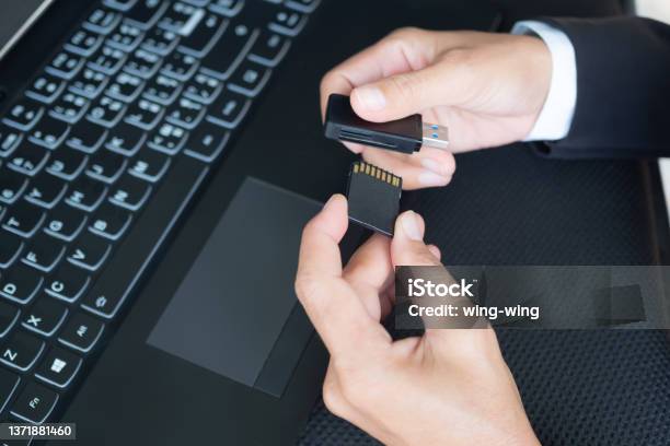Hand With Black Suit Holding Memory Sd Card And Card Reader For Copy Data From Camery To Laptop Computer Stock Photo - Download Image Now