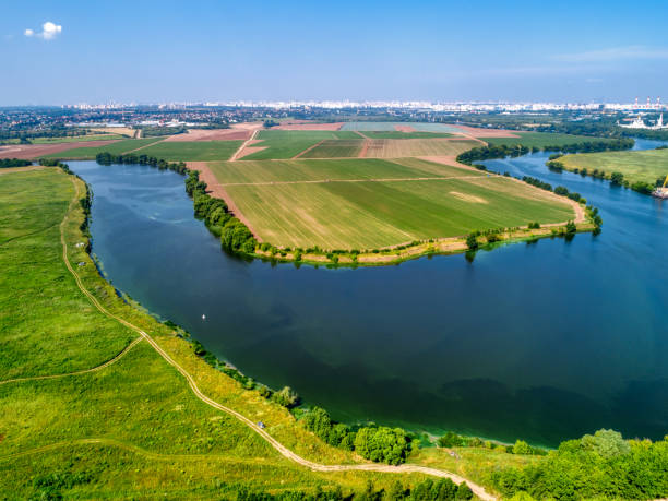 istock Large green field and trees near tranquil river in spring 1371882307