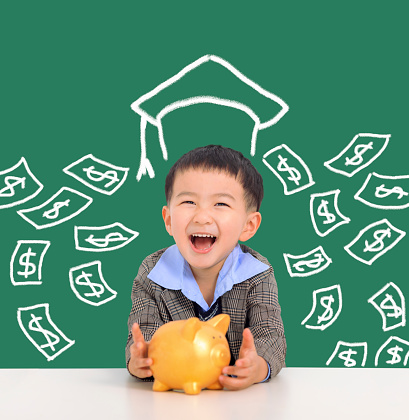 Happy kid holding piggy bank and saving money for education concept
