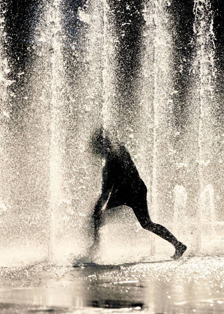 더운 여름날에 시원한 분수의 제트기에서 춤추는 아이의 실루엣 - dancing fountains 뉴스 사진 이미지