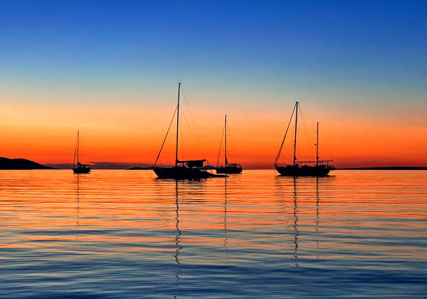 Vertical landscape photography of a sunset with an intense reddish color with the silhouette of a boat in backlight, in the Mar Menor, La Manga, Murcia, Spain