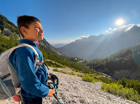 Boy hiking while looking at view during sunrise on mountain, Julian Alps, Slovenia.