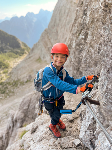 Portrait of boy climbing on a protected climbing route at Via Ferrata Mala Mojstrovka, Julian Alps, Slovenia.