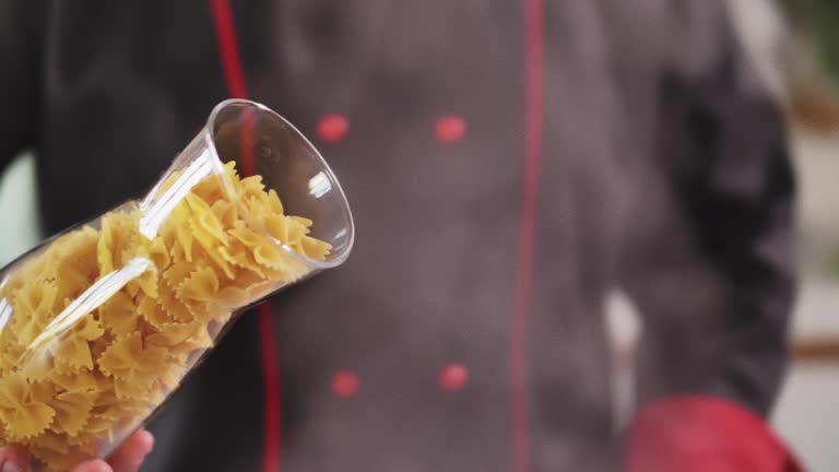 Chef holding bowtie pasta he is about to pour in boiling water