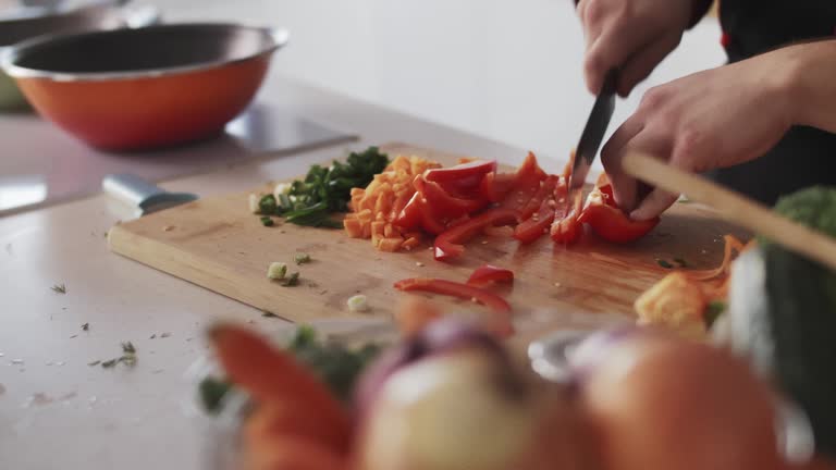 Professional chef slicing up a red bell pepper with a sharp kitchen knife