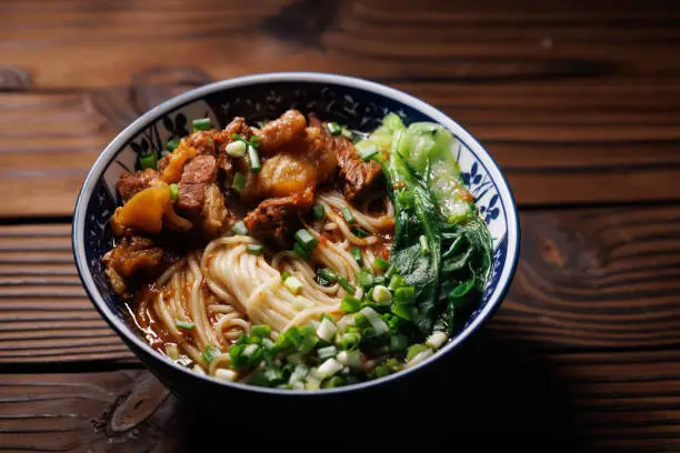 Photo of Asian noodles in broth with slow cooked Beef  On the wooden table