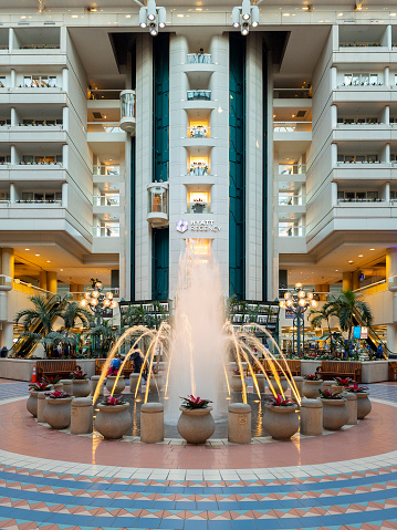 Orlando, Florida - February 9, 2022: Vertical View of Terminal B Main Hall inside Orlando International Airport (MCO) with Fountain in Foreground and Hyatt Regency Hotel in Background.