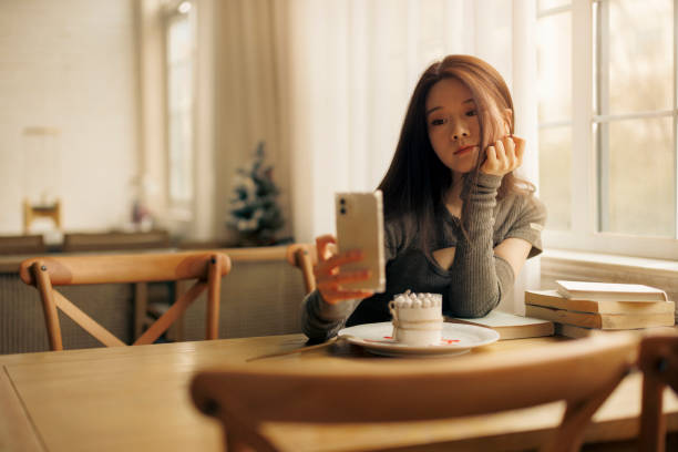 istock Young woman using mobile phone to broadcast live in cafe 1371900670