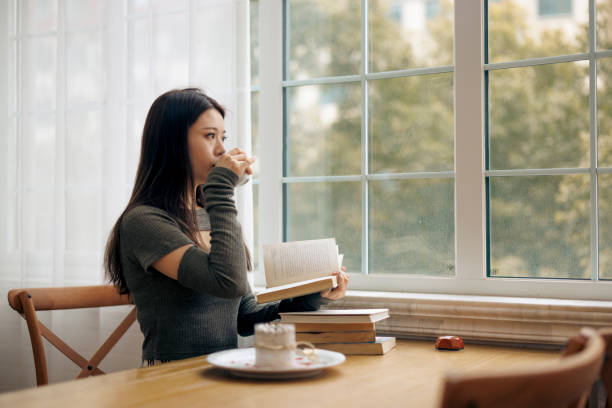 istock young Asian woman reading a book in a cafe 1371900681