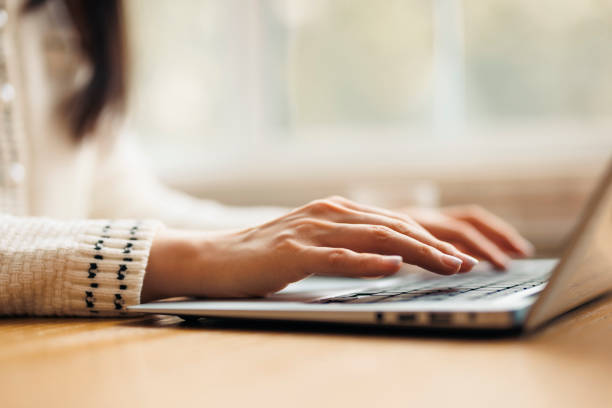 Close up of woman's hands typing on laptop