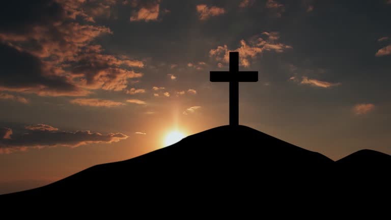 Silhouette of christian cross symbol on the mountain peak at sunset time