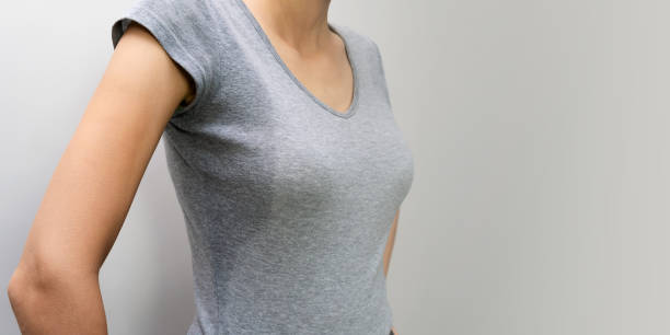 close-up de uma jovem mulher em uma camisa cinza com hiperidrose, suando. jovem mulher caucasiana com manchas de suor em roupas cinza em um fundo claro. conceito de assistência médica. - fotos de stock de suor excessivo e - imagens