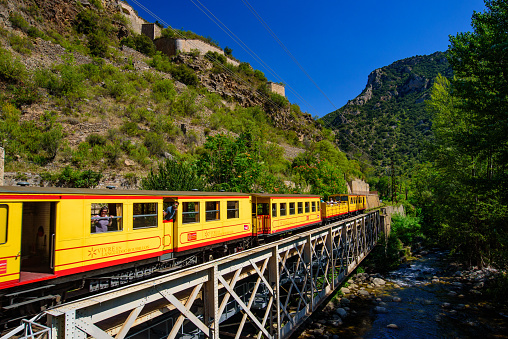 The Little Yellow Train (Le Petit Train Jaune) passing through Villefranche-de-Conflent, France