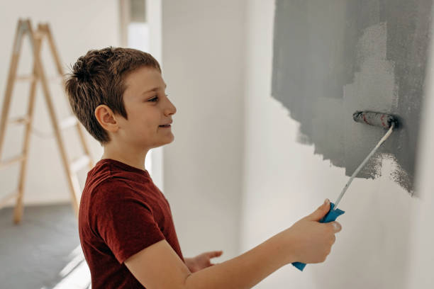 istock Boy paints the wall in white 1371909053