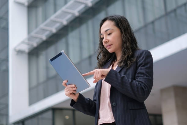 istock Asian Business Woman Using Digital Tablet Outside Her Office Building 1371909658