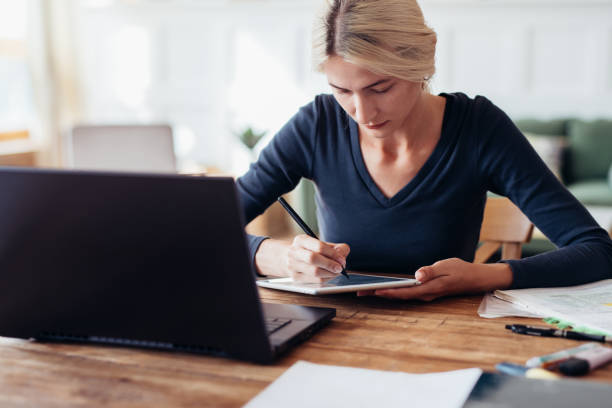 istock Woman studying at home. Female student writing notes on tablet. 1371912052