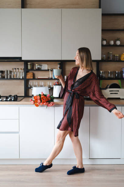 istock Woman having a coffee at home while dancing and enjoying flowers 1371912109
