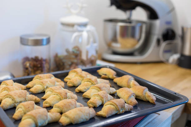 Freshly baked homemade croissants on a baking tin plate on the kitchen table.