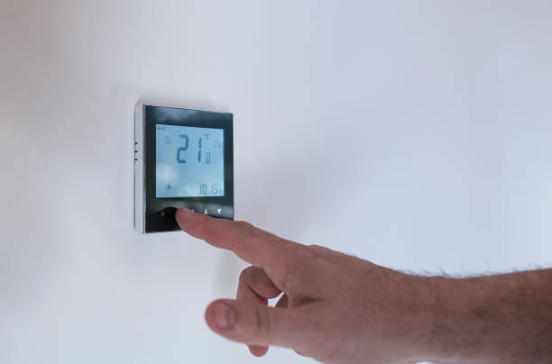 istock Man at home adjusting thermostat with device on the wall. 1371913202