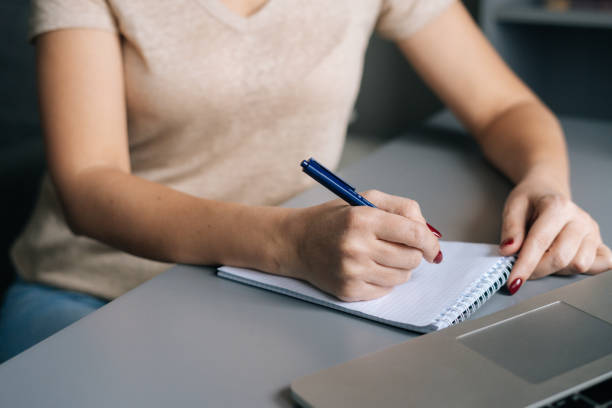 istock Close-up cropped shot of unrecognizable woman write making notes, studying online on laptop at home office. 1371915061