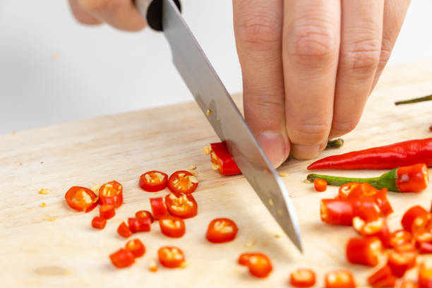 istock woman's hand is using a knife to cut red chili peppers for cooking 1371916423